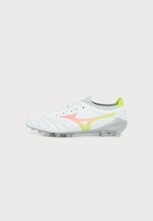 Weißer Fußballschuh mit mehrfarbigem Logo, Schnürsenkeln und Stollen an der Sohle, seitlich auf einfachem Hintergrund dargestellt.