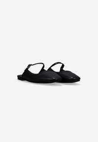 Zapatos planos negros tipo slingback con punta afilada, material de cuero liso y una delgada correa ajustable en el talón.