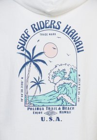 Felpa bianca con un design grafico blu che presenta palme, onde e un sole. Il testo include "Surf Riders Hawaii" e "Polihua Trail & Beach."