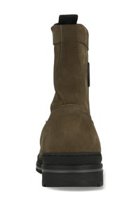 Bruine suède enkellaars met een zachte textuur, zwarte rubberen zool en contrasterende stiksels. Voorzien van een aantrekstrip aan de achterkant voor eenvoudig aan- en uittrekken.