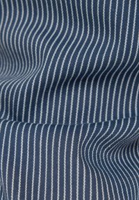 Baumwollstoff in Dunkelblau mit feinen weißen vertikalen Streifen, der eine glatte Textur und ein leicht wellenartiges Muster zeigt.