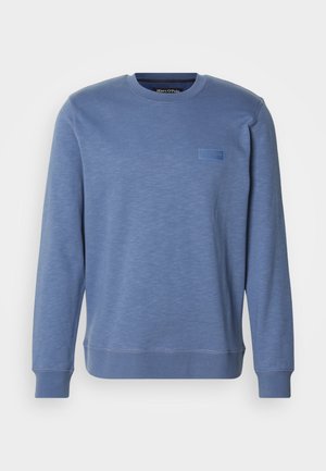 Blaues Crewneck-Sweatshirt aus weichem Stoff, das eine strukturierte Oberfläche und ein dezentes Logo-Patch auf der Brust hat. Gerippte Bündchen und Saum.