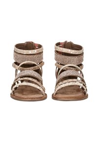 Para beżowych sandałów odkrytych palców z wieloma zdobionymi paskami, które zawierają cyrkonie i ćwieki oraz zawiązaniami na kostkach.