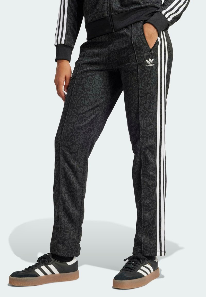 Čierne nohavice na behanie s bielymi bočnými pruhmi, dvoma vreckami, elastickým pásom a logom Adidas na ľavom boku.