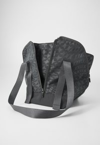 Grå totebag med geometrisk mønster, med dobbel glidelås, flate stropper og en strukturert form. Innvendig er den uten foring, med romslig design.