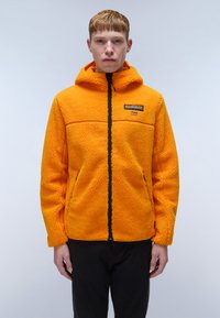 Orange fleecejacka med huva, svart dragkedja och strukturerad finish. Har en broderad patch på bröstet och en avslappnad passform.