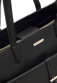 Sac à main en cuir noir avec une forme structurée, anses supérieures, fermeture éclair dorée et une plaque logo en métal poli. Texture lisse sans motifs visibles.