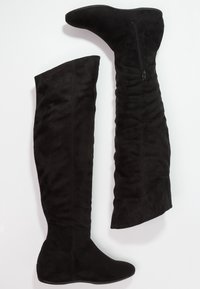 Botas negras de ante por encima de la rodilla con una textura suave y un cierre lateral, que presentan una silueta ajustada y puntera redondeada.