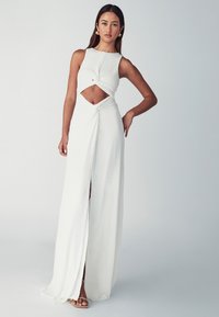 Vestido blanco con un corsé ajustado, detalles recortados y una abertura frontal. Hecho de una tela suave con un diseño drapeado y cintura ceñida.