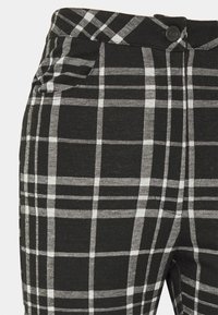 Svart och vit rutiga byxor med knäppning, framfickor och slät yta. Detaljerat rutmönster med kontrasterande linjer.