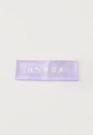 Hellviolettes Sport-Stirnband mit kleinem Punktemuster und weißem Puma-Logo sowie "HYROX"-Text auf der Vorderseite, vor einfarbig weißem Hintergrund.