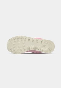 Semelle d'une basket rose avec une semelle extérieure en caoutchouc beige présentant des crampons profonds et un petit logo New Balance près du talon.