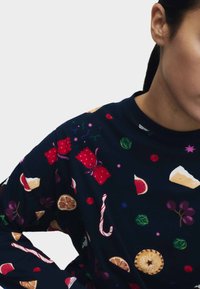 Sudadera negra con un estampado colorido de tela que muestra varios alimentos, incluidos dulces y frutas, con cuello redondo y mangas largas.