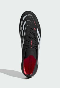 Μαύρο αθλητικό παπούτσι με υφασμένο επάνω μέρος, τρεις λευκές ρίγες, κόκκινες λεπτομέρειες και εφαρμοστή εφαρμογή. Διαθέτει ξεκάθαρο, εργονομικό σχέδιο.