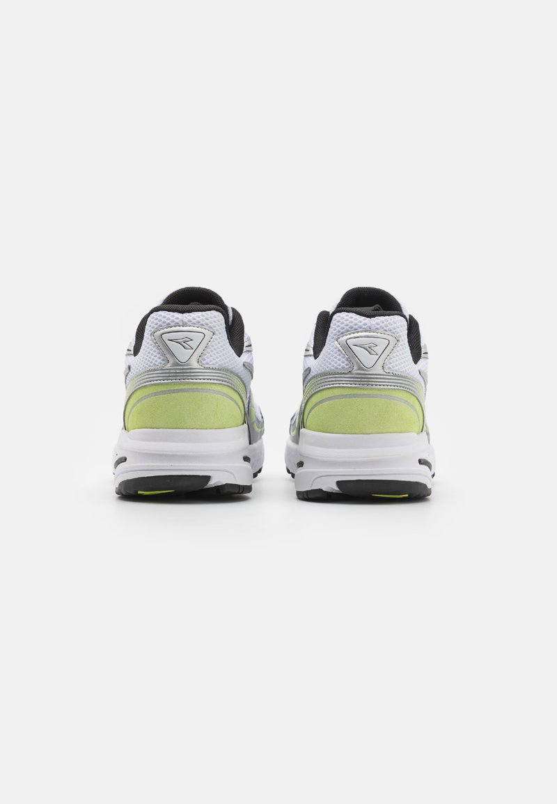 Witte sportschoenen hebben een bovenwerk van mesh met zwarte accenten, een neon groene hielpaneel en een rubberen buitenzool met een geprofileerd loopvlak.