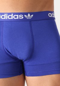 Lila pamut boxer alsónemű széles fehér derékgummival, amelyen az "adidas" logo és három csík található. Simaság és formázott dizájn jellemzi.