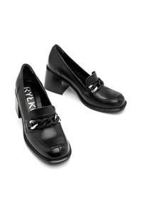 Czarne skórzane buty na obcasie z zaokrąglonym noskiem, z teksturowaną cholewką i dekoracyjnym łańcuchem na przodzie.