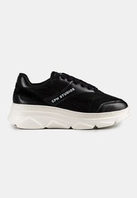 Baskets de sport noires en mesh et cuir, avec une épaisse semelle en caoutchouc blanc et le texte "CPH STUDIOS" sur le côté.