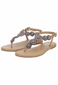 Sandali piatti color tan con embellishments in perline e pietre, caratterizzati da motivi circolari. Suola piatta e chiusura a fibbia sul cinturino alla caviglia.