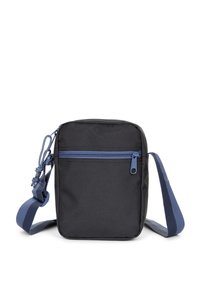 Černá látková taška přes rameno s modrým zipem, obdélníkový tvar, nastavitelný popruh a přední kapsa na zip. Hladká textura, minimalistický design.