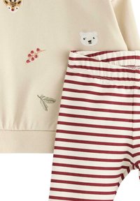 Cream sweatshirt with animal embroidery and red striped leggings. Soft fabric, ribbed cuffs, and elastic waistband on pants.