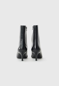 Stivaletti neri in pelle con un design elegante, punta affusolata e tacchi alti e sottili. Presentano una zip laterale per una facile vestibilità.
