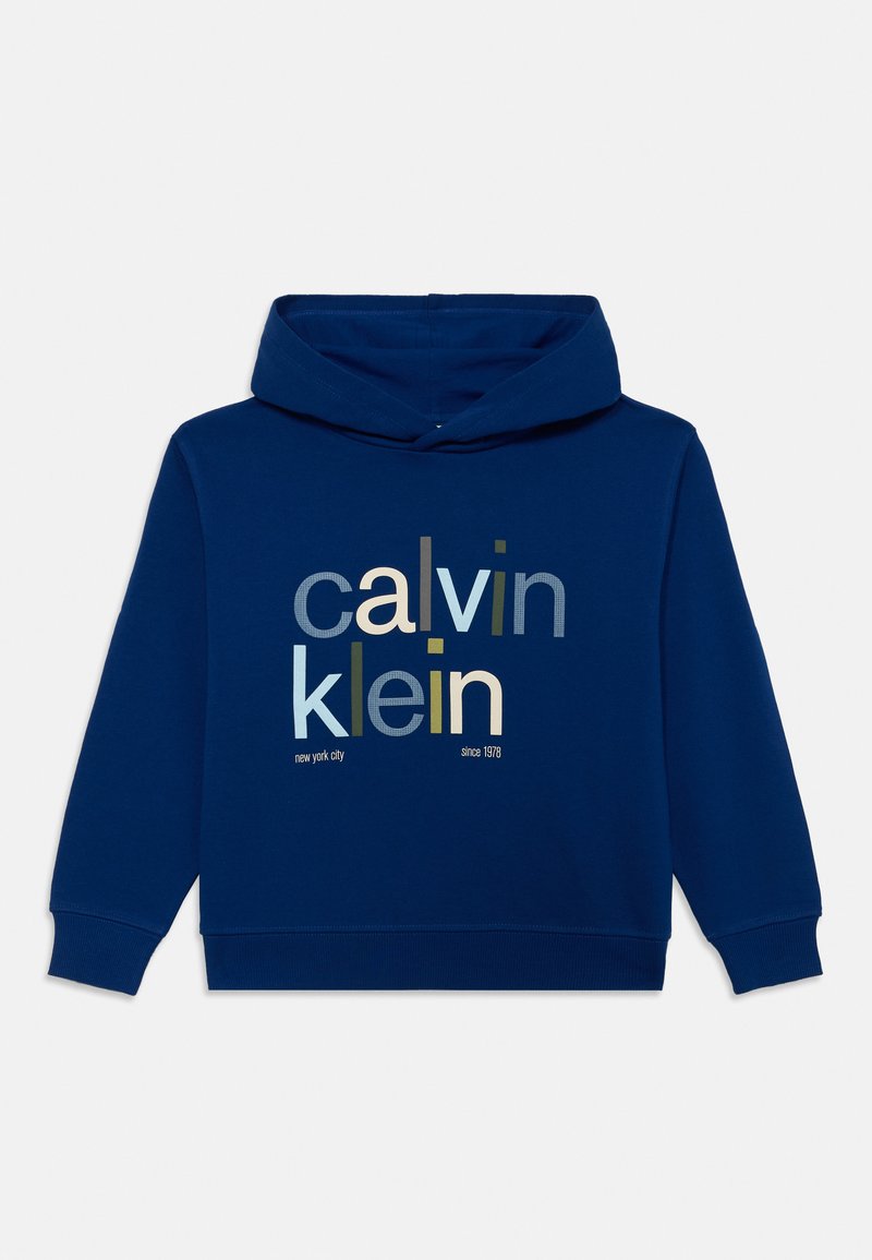Tums zilas kapucīna krekls izgatavots no kokvilnas, ar priekšējo attēlu, kurā attēlots "calvin klein" dažādos fontos un krāsās, un teksts "new york city since 1978".