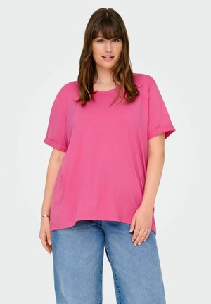 Locker sitzendes pinkes T-Shirt mit rundem Halsausschnitt und hochgerollten kurzen Ärmeln, aus weichem Material; kombiniert mit hellblauen weiten Jeans.