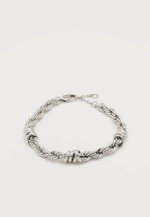 Zilveren gedraaide touwarmband met drie gladde knoopaccenten en een karabijnsluiting met verlengketting op een witte achtergrond.