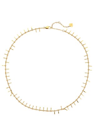 Close-up van een hand met Franse manicure die een delicaat gouden ketting met kleine hangers aanraakt bij een persoon die een witte top draagt.
