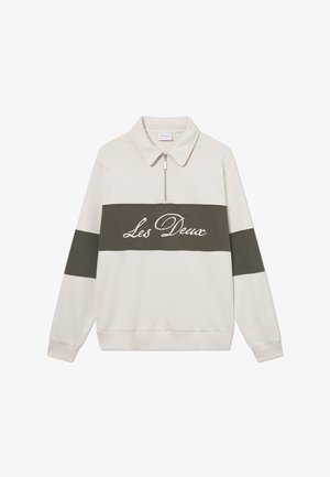 Világos bézs pulóver cipzárral a nyaknál, sötét olívazöld vízszintes csíkkal és fehér "Les Deux" felirattal a mellkasán. Puha textúra.