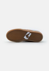 Brown rubber sole with a herringbone pattern, featuring a gray textile upper and a white accent logo on the side.