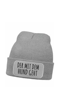 Gray knitted beanie with a folded cuff and a rectangular patch featuring black text: "DER MIT DEM HUND GEHT." Text is centrally placed on the patch.