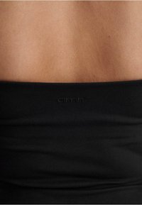 Black elastic waistband with a smooth texture and subtle gathers, featuring the logo "aimn" embossed in a discrete manner.