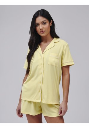 Gult, kortærmet pyjamasæt med en knaplukket top og lomme. Fremstillet i et tekstureret stof med kontrasterende hvid kant omkring kraven og lommen.