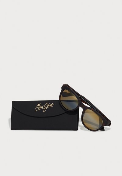 Lunettes Maui Jim avec monture en écaille de tortue, verres bruns dégradés et étui noir avec logo doré. Design moderne et audacieux.