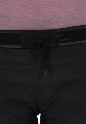 Black padded shorts feature a textured waistband with a black drawstring. The material appears smooth with a sleek design and minimal accents.