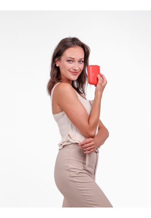 Red leather wallet with a smooth texture and subtle branding, held by a person wearing a knitted beige top and beige pants.