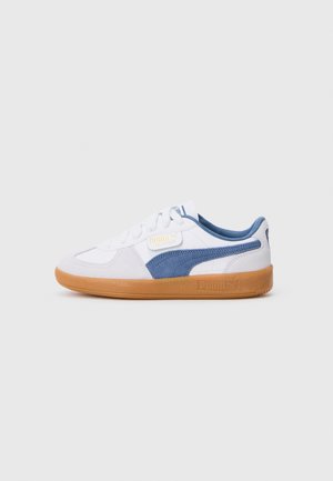 White sneaker with blue suede accents, textured rubber sole, and lace-up design. Features a PUMA logo tag on the side.