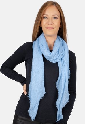 Light blue scarf with a textured weave and frayed edges, displayed draped around the neck, set against a neutral background.