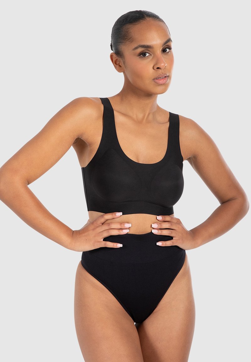 Sujeta negra deportiva con tirantes anchos y escote redondeado, combinada con braguitas negras de talle alto que tienen una textura suave y sin costuras.