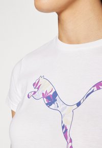 Bílá bavlněná tričko s logem v květinovém vzoru v purpurové, modré a růžové barvě, které zdůrazňuje dynamický design siluety zvířete.