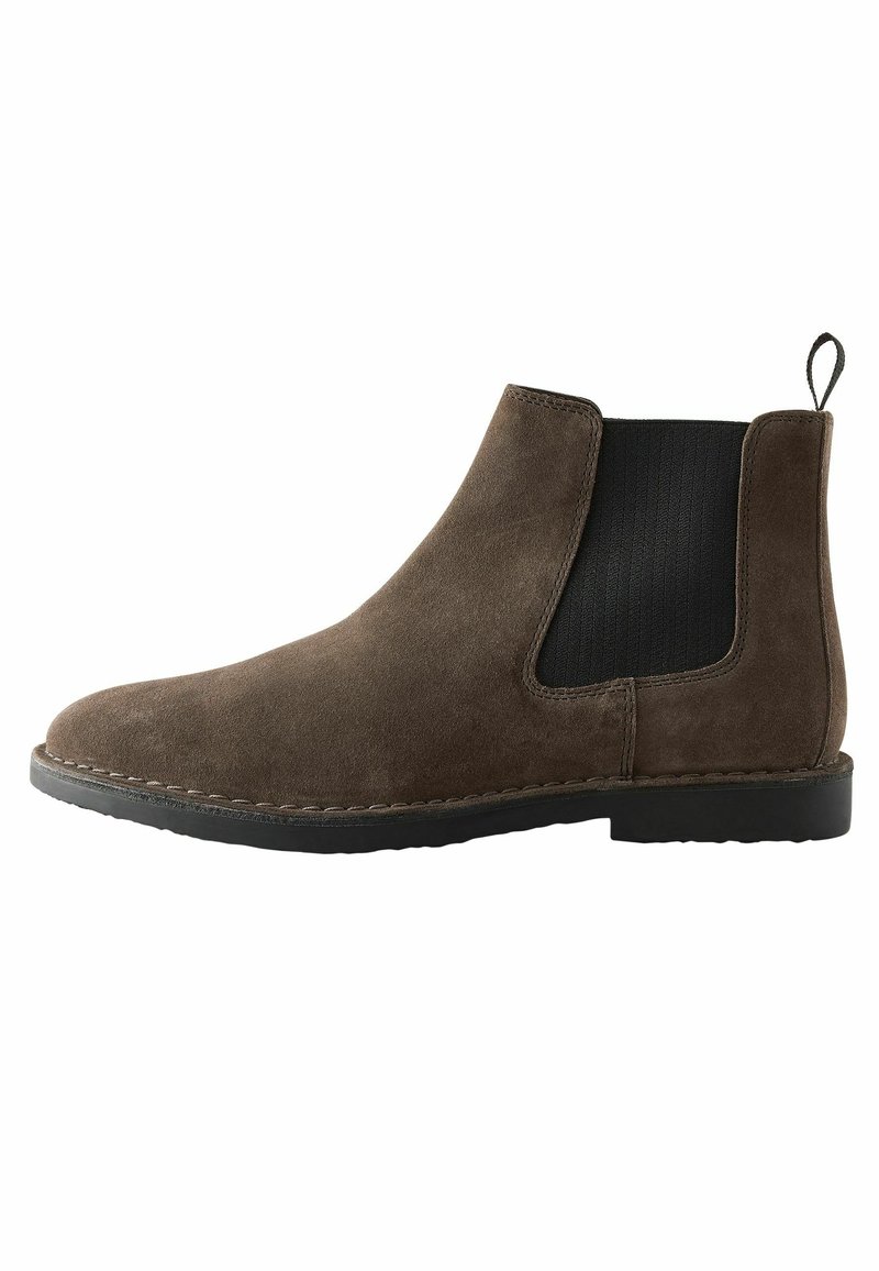 Bottines Chelsea en cuir suédé marron avec des panneaux latéraux en élastique, une languette de traction, un bout rond et une semelle en caoutchouc noir. Finitions de couture le long du bord de la semelle.
