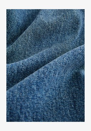 Material denim în nuanțe variate de albastru, cu o textură netedă; prezintă modele de țesătură diagonale și variații subtile în culoare și umbrire.