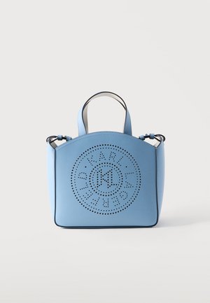 Sac à main en cuir bleu clair avec doubles poignées et design de logo circulaire perforé sur le devant, sur un fond clair uni.