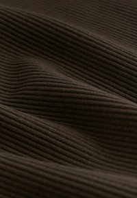 Tela marrón acanalada con líneas verticales prominentes, que presenta una superficie texturizada y suave con ligeras ondas, capturando profundidad en color y patrón.