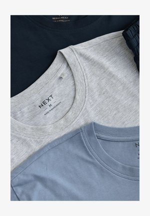 Kolm ümmarguse kaelusega t-särki, hunnikus: üks tumesinine, üks helesinine ja üks helekrae. Kõik on tavalise lõikega, valmistatud pehmest ja siledast kangast.