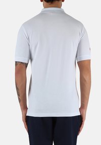 Polo shirt bianco con colletto classico, maniche corte e dettagli del logo discreti sulla manica. Materiale morbido e leggero.