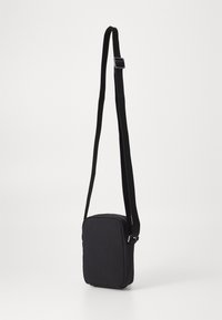 Borsa a tracolla rettangolare nera con chiusura a zip, realizzata in tessuto testurizzato, dotata di una lunga tracolla regolabile e di un design minimalista.