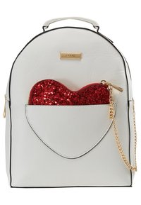 Sac à dos en cuir blanc avec une poche avant en forme de cœur contenant une pochette rouge pailletée et un détail de chaîne dorée.